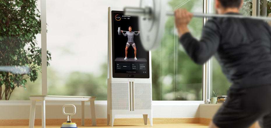 Person working out using barbell weights in front of a Tempo home gym system.