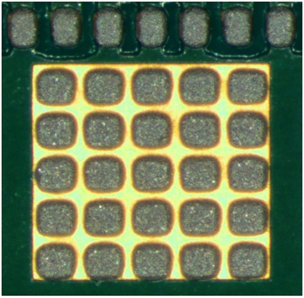 Figure 11. Example of wet solder paste (prior to reflow) on a copper ground pad that has been deposited by a solder stencil with multiple smaller apertures for the ground pad. Signal pins are shown at the top of the picture for reference.