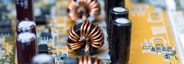 Circuit board with copper coils, capacitors, and components on yellow background.