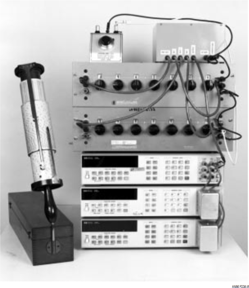 図C8．サブppmの直線性を備えた電圧源。右上の筐体はLTZ1000Aを用いたリファレンスとバッファ。左上はオフセット・トリマ。リファレンスとメイン・ケルビン・バーレイ分圧器は写真中央のそれぞれ上と中央。3 台のHP3458デジタル電圧計（DVM）（写真下）が出力をモニタする。コンピュータ（写真左前列）を使って直線性を計算する