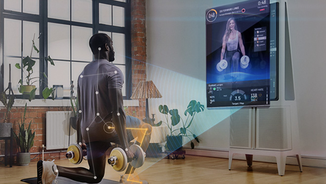 Adult male lunging with dumbbell weights. Exercising in front of a Tempo Studio 'smart' home gym system.